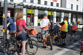 5 Personen mit Plakaten und Sicherheitswesten stehem am Soester Bahnhof und warten auf das Startsignal zur Raddemo Kidical Mass 2020