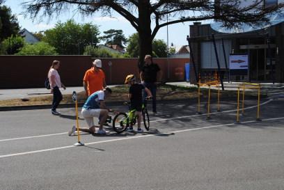 ein Mann kniet beim Kinderfarrad, der Junge schaut zurück wie das Hinterradaufgepunpt wird, Vater, Mutter und ADFC Werl Sprecher schauen zu