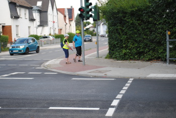 Eva Hoffmann erkundet mit dem Blindenstock in Begleitung von Klaus Kabst den Kreuzungsbereich, um die Grünanforderung der Ampel für den Fußverkehr zu finden.